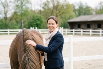 Femme souriante avec un cheval dans une carrière extérieure